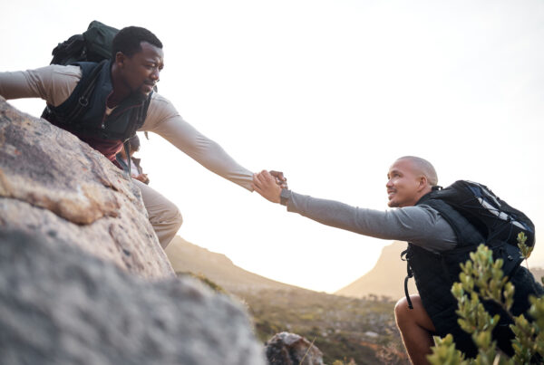 a man helping another man on a hike